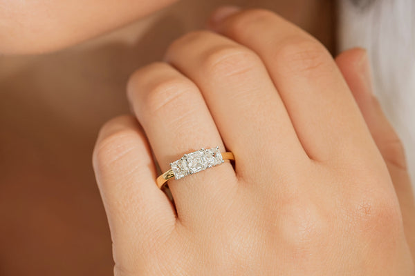 Close up of model wearing three stone asscher cut diamond ring